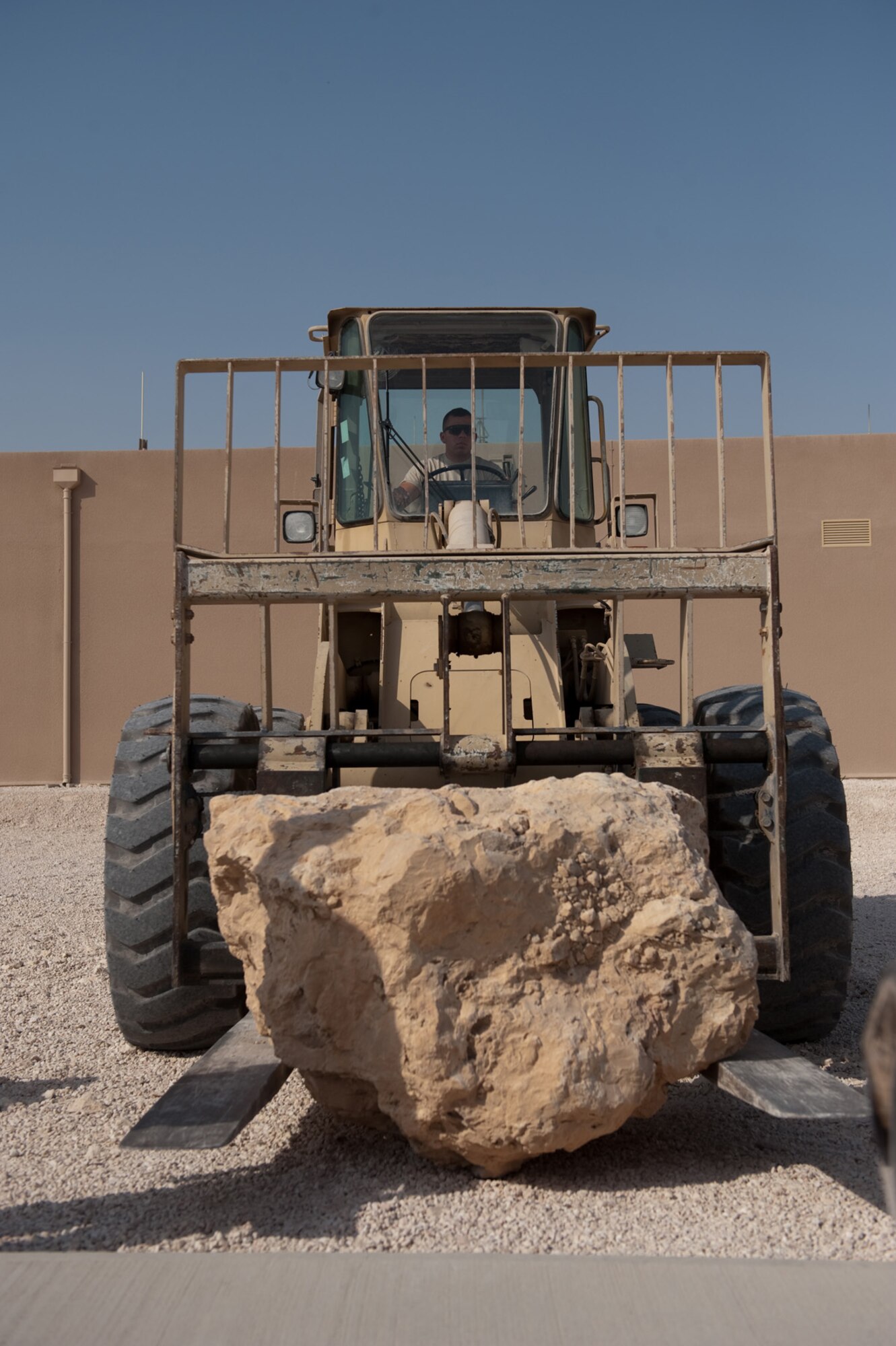 Senior Airman Walter Herandez, 379th Expeditionary Civil Engineer squadron pavement and heavy equipment journeyman, places a boulder, Oct. 11, 2009, in Southwest Asia. The 379 ECES pavement and heavy equipment section placed large boulders around U.S. Air Force assets for an added measure of force protection. (U.S. Air Force photo/Staff Sgt. Robert Barney) 