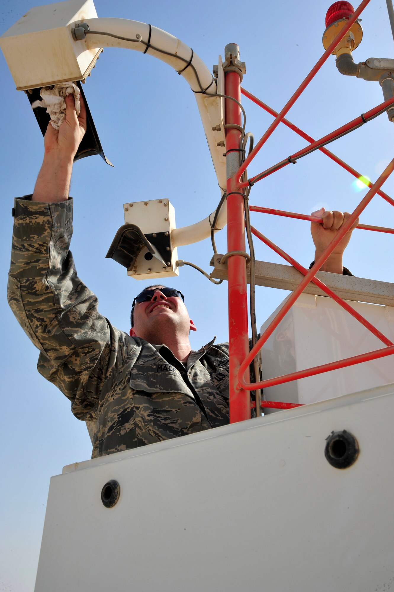 SOUTHWEST ASIA -Staff Sgt. Joshua Mace, 380th Expeditionary Operations Support Squadron weather forecaster, cleans the lenses of a sensor on a fixed meteorological observation system here Oct. 13, 2009. Sergeant Mace is deployed from Beale Air Force Base, Calif., and hails from Eugene, Ore. (U.S. Air Force photo/Tech. Sgt. Charles Larkin Sr)