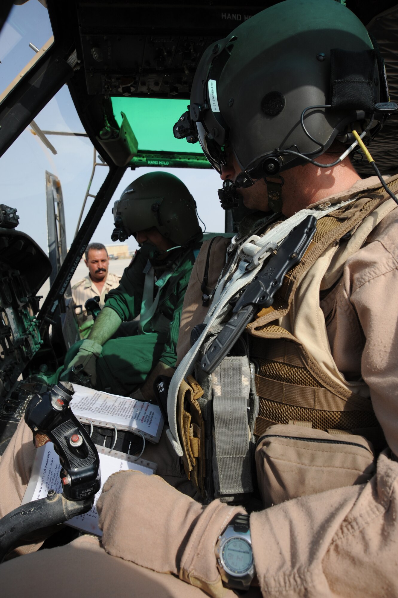 CAMP TAJI, Iraq -- Air Force Maj. Jack Swinehart (right), 721st Air Expeditionary Advisory Squadron UH-1H pilot, observes an Iraqi pilot performing preflight procedures here prior to a helicopter training mission Oct. 8, 2009. The major sits side-by-side with Iraqi pilots as they practice approaches, take-offs, landings and aerial maneuver formation flying procedures. U.S. Air Force instructor pilots assigned to the 721st AEAS train, advise and assist Iraqi helicopter pilots around the clock, helping the Iraqis develop their own air force. Major Swinehart is deployed from and a native of Fort Rucker, Ala. (U.S. Air Force photo/Tech. Sgt. Johnny L. Saldivar)