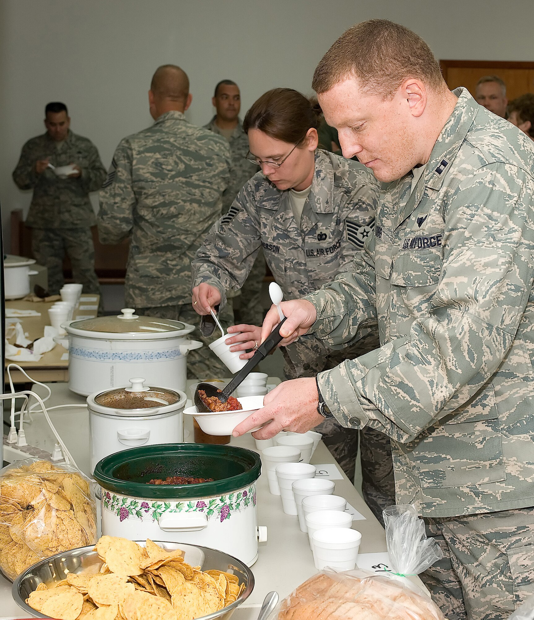 436th Airlift Wing staff members serve chili during their first Chili Cook-off at Chapel 2 Oct. 9. More than 50 people tried 13 pots of chili while three randomly-selected judges determined the winner by color, aroma, taste, after-taste and consistency of the chili. (U.S. Air Force photo/ Jason Minto)
