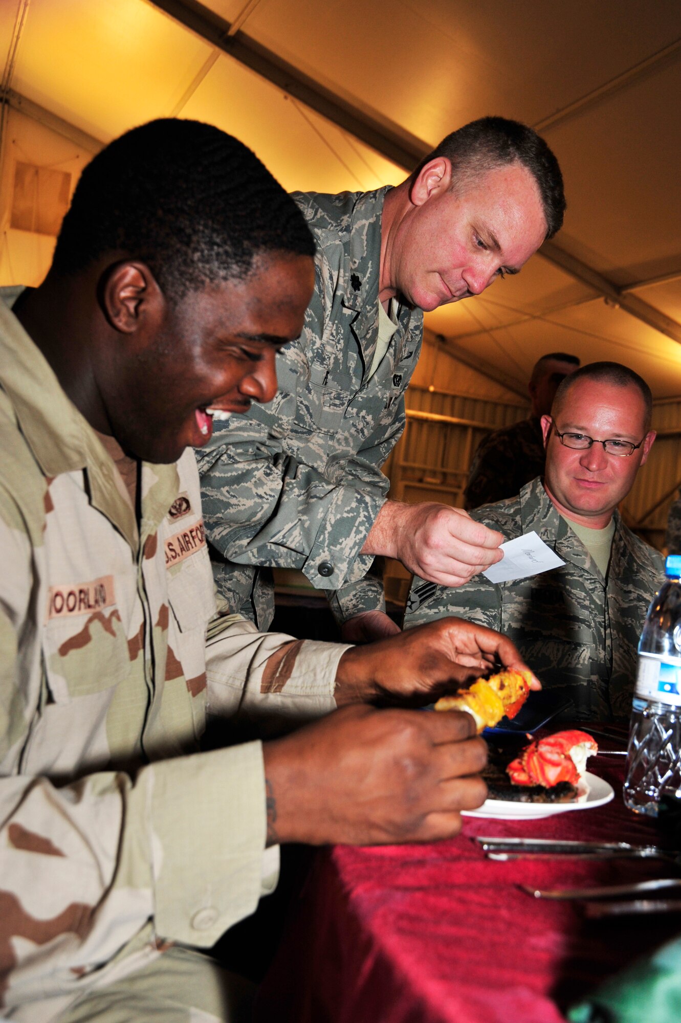 SOUTHWEST ASIA—Airman 1st Class Robert L. Moorland, 380th Expeditionary Civil Engineer Squadron firefighter, receives a birthday dinner from Lt. Col. Daryl A. Page, 380th Expeditionary Operations Support Squadron commander, here Oct. 13, 2009. Colonel Page was one of approximately 30 servers who helped facilitate the wing-wide monthly event. (U.S. Air Force Photo by 2nd Lt. Kidron B. Vestal)