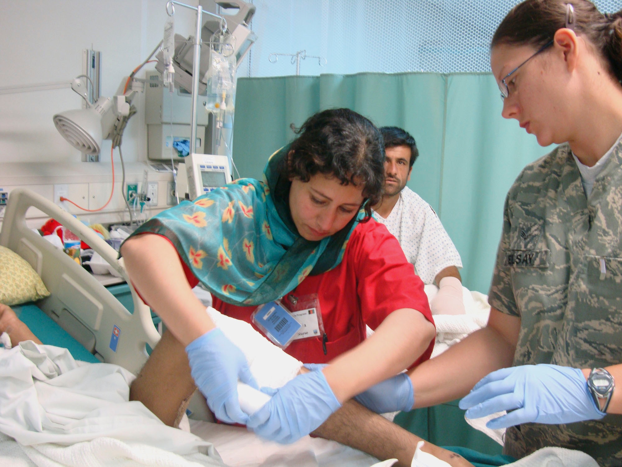 BAGRAM AIRFIELD, Afghanistan -- Laila Farahi (left), a female Afghan National Army soldier, bandages a patient's leg.  She attended a special two-week mentorship program here at the Craig Joint Theater Hospital to work alongside U.S. doctors and nurses to hone her medical skills and get first-hand experience with trauma-based care.  She was one of the first women to ever attend the special program.  (Courtesy photo)                    