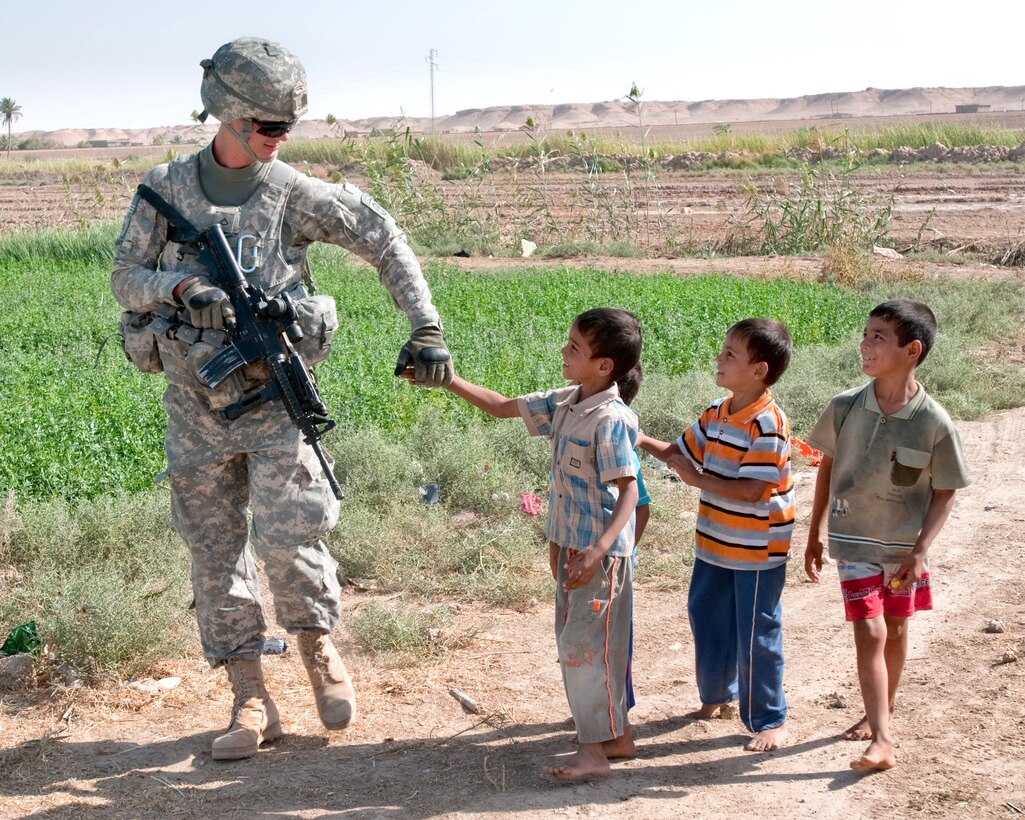 U.S. Army Pfc. Jacob Durant greets Iraqi children while on patrol to assist Iraqi police, who are providing security for a nearby bridge project on the Euphrates River north of Al Taqaddum, Iraq, Oct. 5, 2009. Durant is assigned to the 82nd Airborne Division's Company C, 1st Battalion, 504th Parachute Infantry Regiment, 1st Brigade Combat Team.