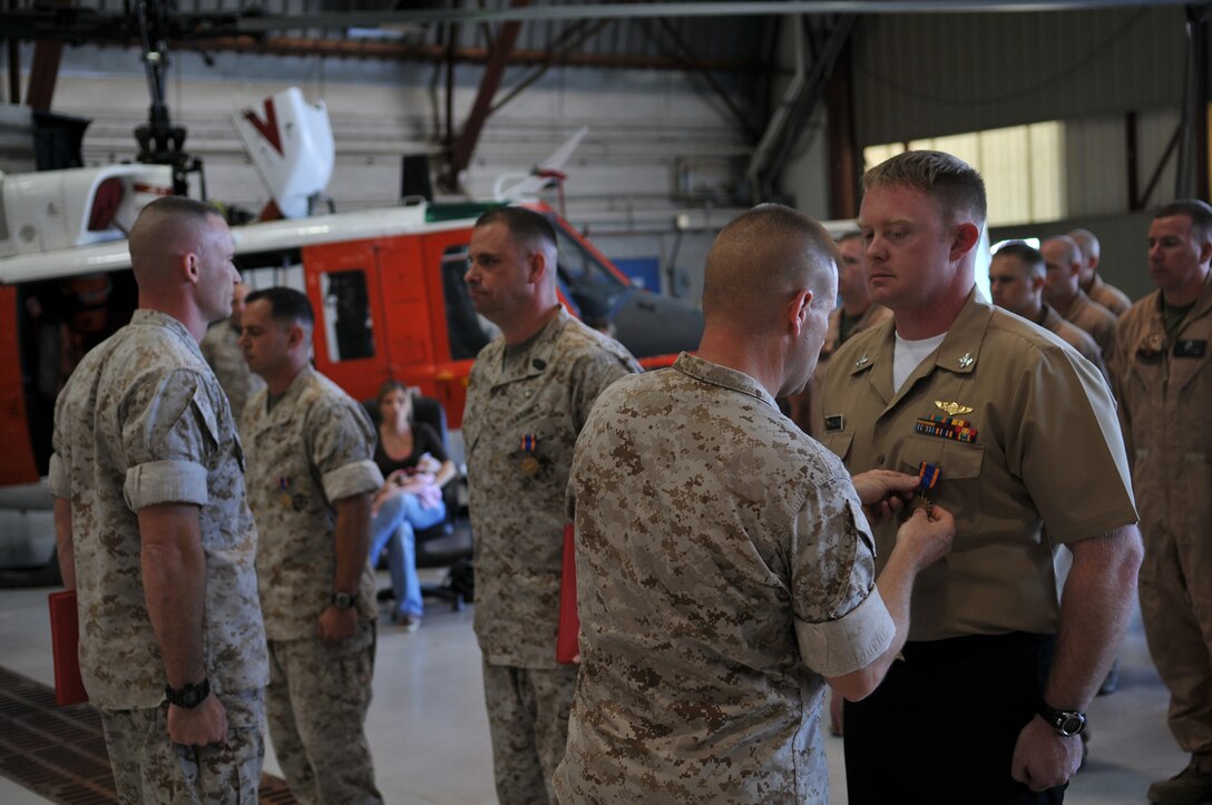 Headquarters and Headquarters Squadron commanding officer pins the Air Medal on Search and Rescue corpsman, Petty Officer 2nd Class Michael Skelton in the SAR hangar at the Marine Corps Air Station in Yuma, Ariz., Oct. 14, 2009. Skelton, along with SAR HH-1N Huey pilot, Capt. Sean Mitzel and SAR maintenance chief, Master Sgt. Russell Reale received the Air Medal for their actions, which led to the rescue of a fellow SAR air crewman during the Huey helicopter crash here in 2007.