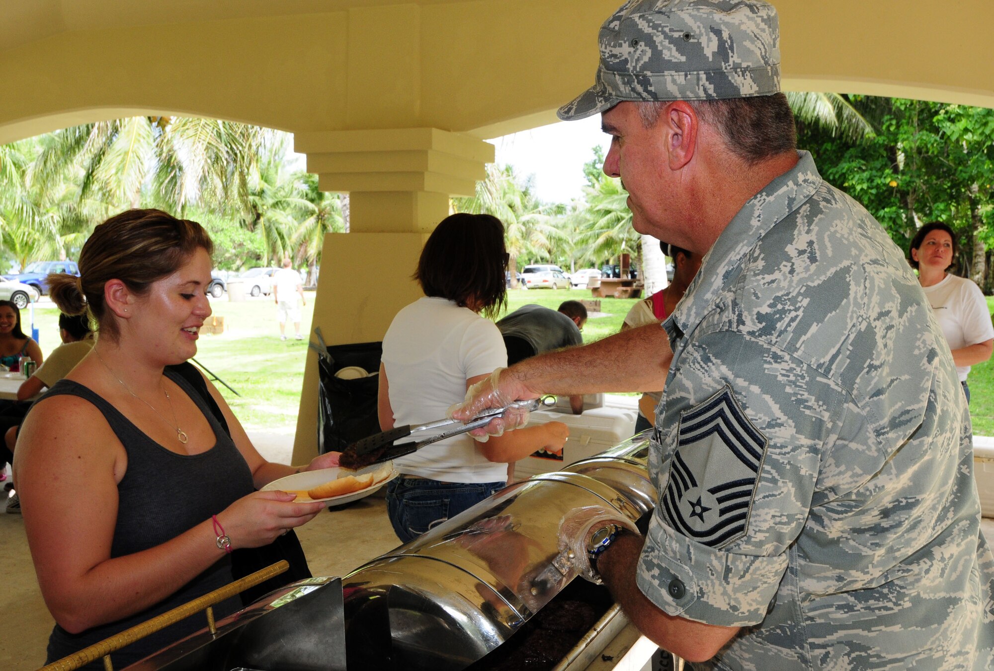 ANDERSEN AIR FORCE BASE, Guam - Chief Master Sgt. Tim Byrd, 36th Maintenance Group superintendent, serves a hamburger to Airman 1st Class Kristin Starkey, 36th Force Support Squadron, Oct. 9 at Tarague Beach pavilion here during Junior Enlisted Appreciation Day. Team Andersen chiefs served Airmen as their way of giving back to the junior enlisted personnel. (U.S. Air Force photo by Airman 1st Class Julian North)
