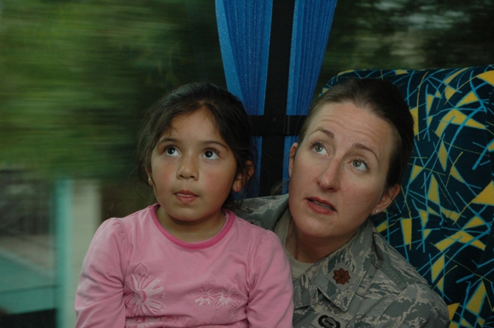 SANTIAGO, Chile -- Maj. Jana Nyerges, a member of Air Forces Southern participating in subject matter exchange with the Chilean Air Force in Santiago, Chile, and her new-found friend, a child from the Centro Comunitario Angels, or 'Angels Community Center' watch cartoons on the bus after spending the day at the Museo Interactivo Mirador.  A group of Airmen sponsored children from the school to visit the museum after landing in country only a few hours.  (Courtesy photo)