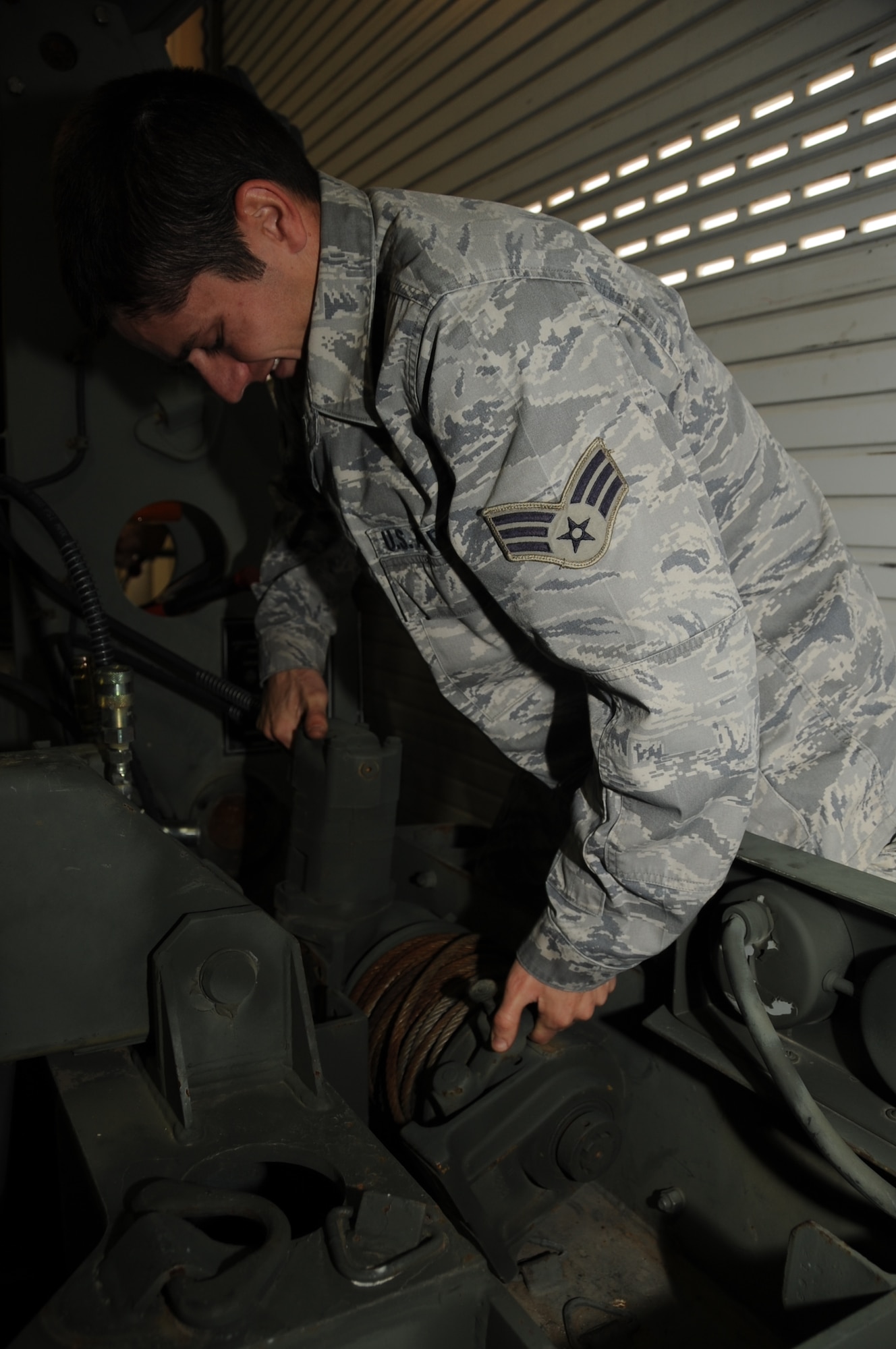 ELLSWORTH AIR FORCE BASE, S.D. -- Senior Airman Adam McCary, 28th Civil Engineer Squadron electrical power production journeyman, pulls out a winch that blocks a roller sheave on a mobile aircraft arresting system, Oct. 15.  Airman McCary removes the roller sheaves during a maintenance checkup which occurs every three years on the MAAS. (U.S Air Force photo/Airman 1st Class Anthony Sanchelli)