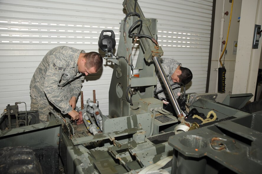 ELLSWORTH AIR FORCE BASE, S.D. -- (Left to right) Airman 1st Class Christopher Bratton and Senior Airman Adam McCary, 28th Civil Engineer Squadron electrical power production members, unscrew bolts to roller sheaves before removing them from a mobile aircraft arresting system, Oct. 15.  The roller sheaves, when in place, run a large belt through the MAAS. (U.S Air Force photo/Airman 1st Class Anthony Sanchelli)