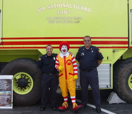 128th Firefighters Ricardo Martinez left, and Barry Alberts pose with Ronald McDonald during Cudahy's Fire Safety Day September 26, 2009. Firefighters Martinez and Alberts displayed the wing's P-23 crash truck during the event and provided tours and information to those in attendance. 