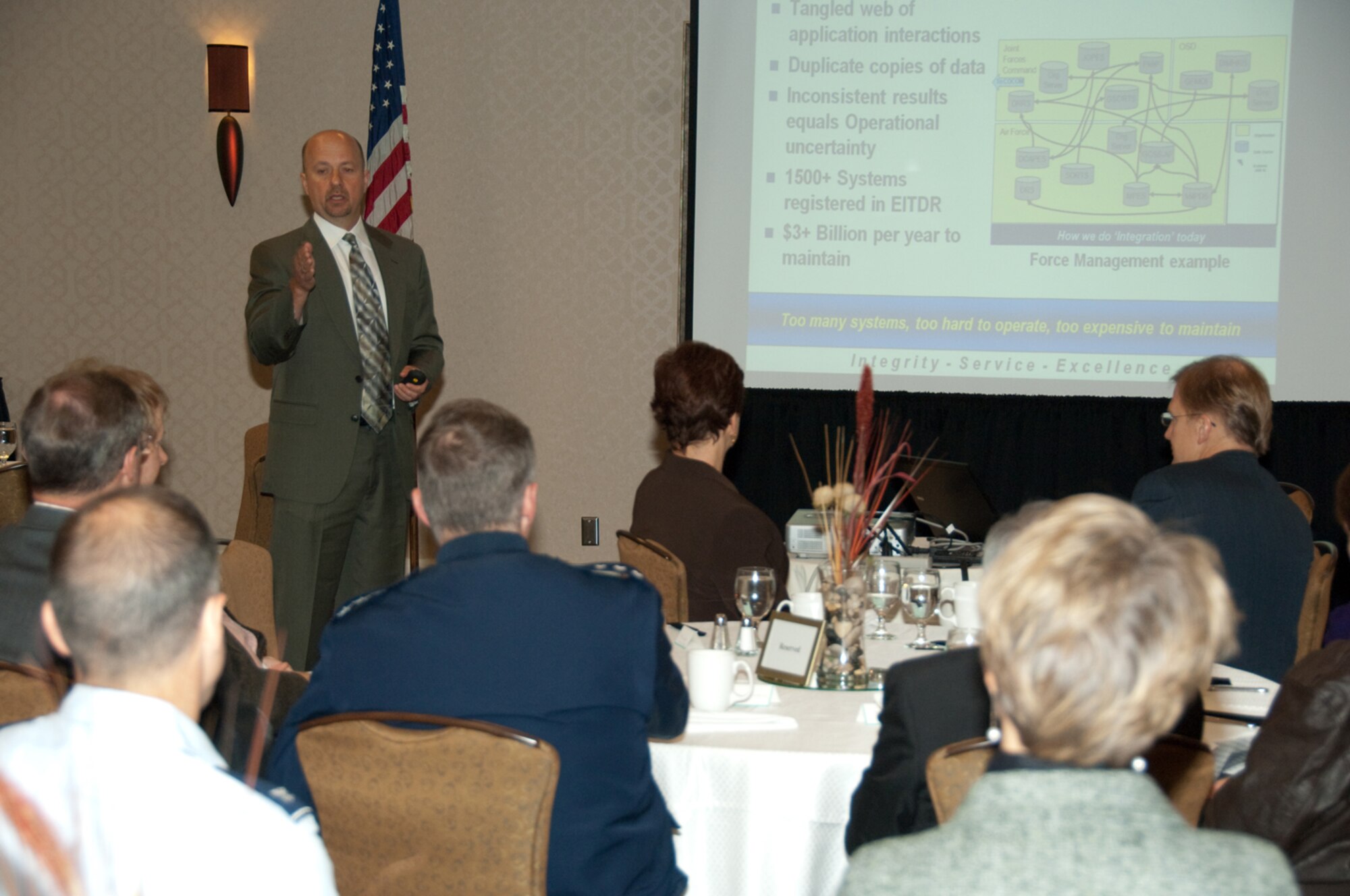 HANSCOM AIR FORCE BASE, Mass. -- Mike Corrigan of Sumaria Systems, a senior information strategist within the Undersecretary of the Air Force’s Chief Management Office, briefs key Electronic Systems Center leaders and industry members during a Military Affairs Council breakfast meeting in Bedford Oct. 14.  Dr. Scott Renner of MITRE also provided a briefing, discussing the history of, and current implementation efforts for, network-centric operations.  (Photo by Rick Berry)