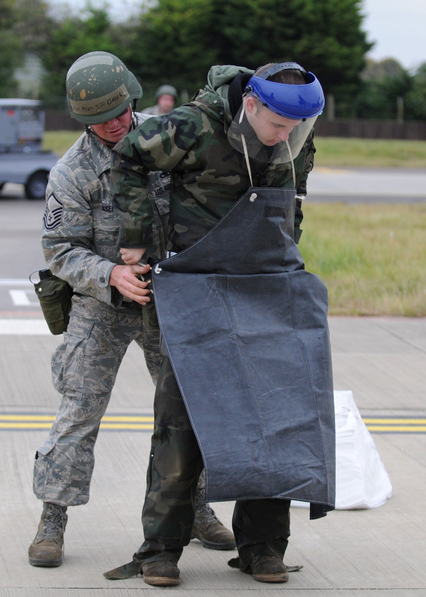 RAF MILDENHALL, England – Master Sgt. John Kinser, 100th Aircraft Maintenance Squadron production superintendent, helps Airman 1st Class Dakota Price with personal protection equipment to help clean a simulated fuel spill during the Operational Readiness Inspection Oct. 14. (U.S. Air Force photo/ Staff Sgt. Jerry Fleshman)