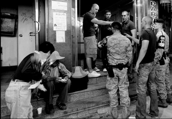 Two security forces Airmen interrupt a heated conversation outside a bar during their nightly patrol of Songtan Entertainment District outside Osan Air Base, Republic of Korea. Town Patrol is a volunteer position for the Security Forces Airmen here. Teams work together in different areas every night. Their job consists of force protection, blocking traffic within the walking areas and patrols of the many bars, restaurants and off limit areas. While traveling through the streets to each of the facilities, they stay aware of everyone and everything with the primary goal of ensuring safety. ( U.S. Air Force photo/ Senior Airman Stephenie Wade)

