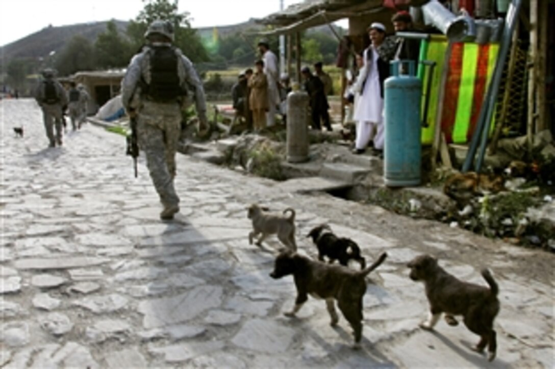 Dogs follow U.S. Army soldiers as they patrol through a village near Combat Outpost Herrera in Paktiya province, Afghanistan, Oct. 13, 2009. The soldiers are deployed with Apache Troop, 1st Squadron, 40th Cavalry Regiment. 