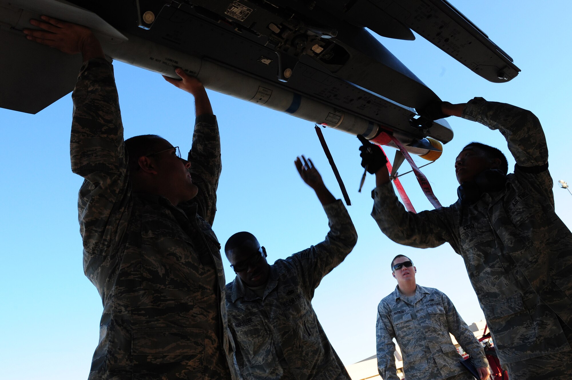 NELLIS AIR FORCE BASE, Nev.-- Load crew members from the 757th Aircraft Maintenance Squadron load a missile onto an F-15 Strike Eagle while Senior Airman Jeffrey Matheney observes their performance during the Weapons Load Crew Competition on the Nellis  flight line, Oct. 9. The quarterly weapons load crew competition tests the skills of airman on six different teams. The Airmen are judged on speed, accuracy and safety.
(U.S. Air Force Photo / Staff Sgt. William P.Coleman)
