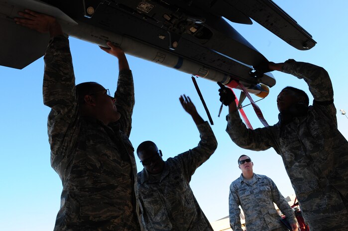 NELLIS AIR FORCE BASE, Nev.-- Load crew members from the 757th Aircraft Maintenance Squadron load a missile onto an F-15 Strike Eagle while Senior Airman Jeffrey Matheney observes their performance during the Weapons Load Crew Competition on the Nellis  flight line, Oct. 9. The quarterly weapons load crew competition tests the skills of airman on six different teams. The Airmen are judged on speed, accuracy and safety.
(U.S. Air Force Photo / Staff Sgt. William P.Coleman)