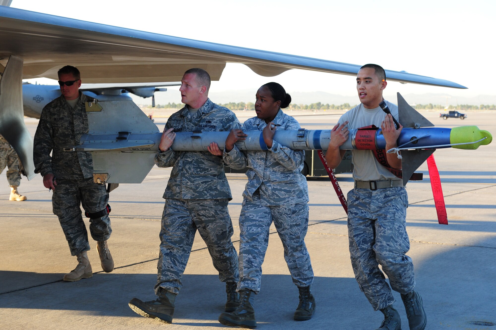 NELLIS AIR FORCE BASE, Nev. --  Staff Sgt. Christopher Helenek, Senior Airman Danielle Griffin and Airman 1st Class Ryan Deocampo, load crew members from the 422nd Test and Evaluation Squadron, carry an AIM 9 missile to an F-22 Raptor during the Weapons Load Crew Competition on the Nellis flight line, Oct. 9. The quarterly weapons load crew competition tests the skills of Airmen on six different teams. The airman are judged on speed, accuracy and safety. The all Airmen team went on to win the competition.
(U.S. Air Force Photo / Staff Sgt. William P.Coleman)