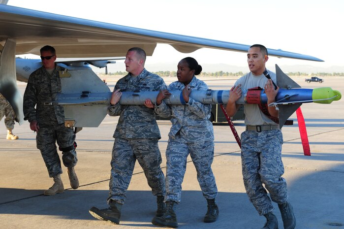 NELLIS AIR FORCE BASE, Nev. --  Staff Sgt. Christopher Helenek, Senior Airman Danielle Griffin and Airman 1st Class Ryan Deocampo, load crew members from the 422nd Test and Evaluation Squadron, carry an AIM 9 missile to an F-22 Raptor during the Weapons Load Crew Competition on the Nellis flight line, Oct. 9. The quarterly weapons load crew competition tests the skills of Airmen on six different teams. The airman are judged on speed, accuracy and safety. The all Airmen team went on to win the competition.
(U.S. Air Force Photo / Staff Sgt. William P.Coleman)
