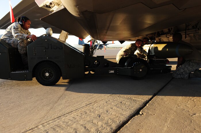 NELLIS AIR FORCE BASE, Nev.-- Staff Sgt. Christopher Helenek, Senior Airman Danielle Griffin and Airman 1st Class Ryan Deocampo, load crew members from the 422nd Test and Evaluation Squadron, load a bomb onto an F-22 Raptor during the Weapons Load Crew Competition on the Nellis  flight line, Oct. 9. The quarterly weapons load crew competition tests the skills of airman on six different teams. The Airmen are judged on speed, accuracy and safety. The all Airmen team went on to win the competition.
(U.S. Air Force Photo / Staff Sgt. William P.Coleman)