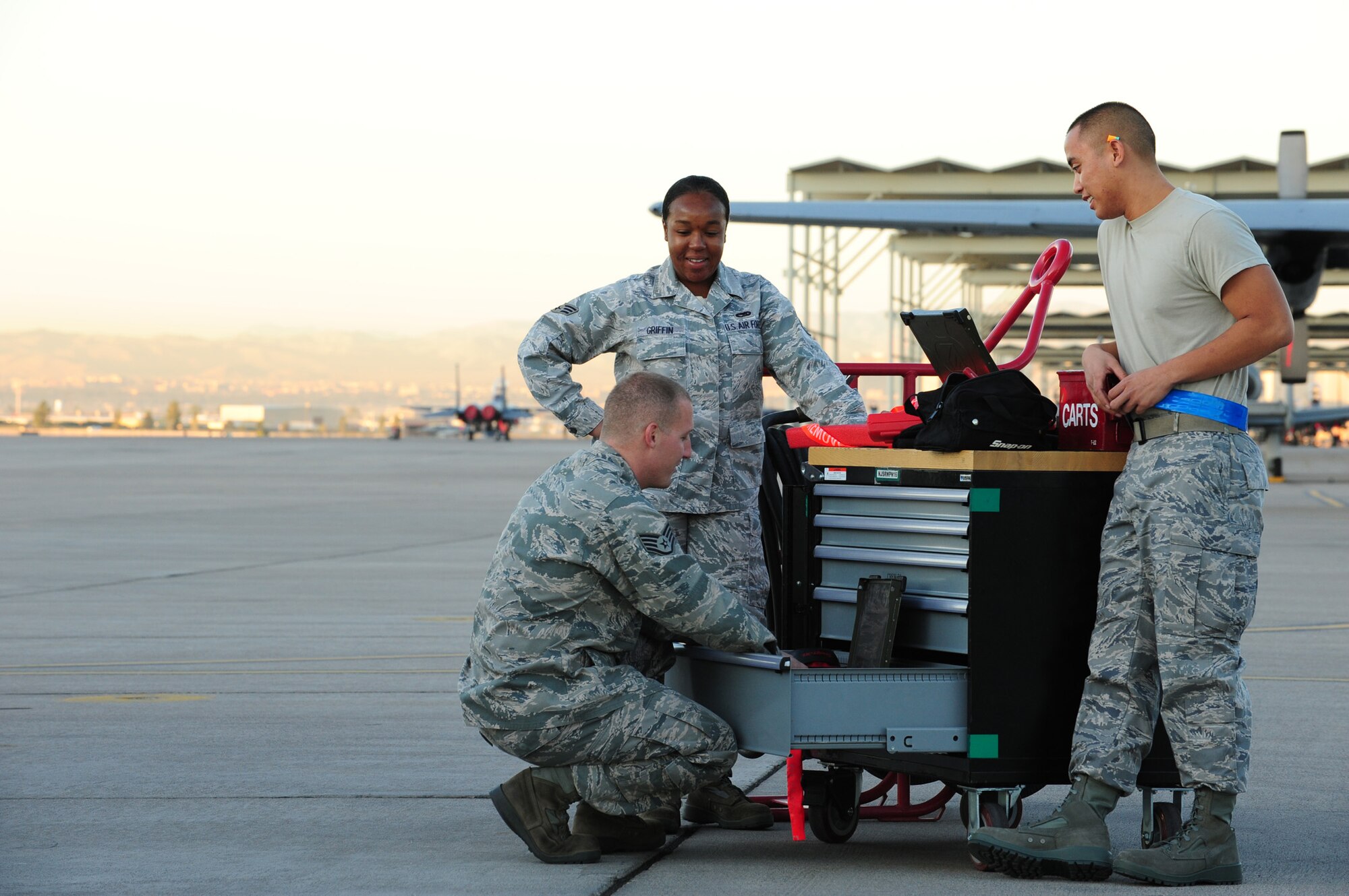 NELLIS AIR FORCE BASE, Nev. -- Staff Sgt. Christopher Helenek, Senior Airman Danielle Griffin and Airman 1st Class Ryan Deocampo, load crew members from the 422nd Test and Evaluation Squadron, share a few laughs before the Weapons Load Crew Competition on the Nellis flight line, Oct. 9, 2009. The quarterly weapons load crew competition tests the skills of airman on six different teams. The Airmen are judged on speed, accuracy and safety. The all Airmen team went on to win the competition.
(U.S. Air Force Photo / Staff Sgt. William P.Coleman)