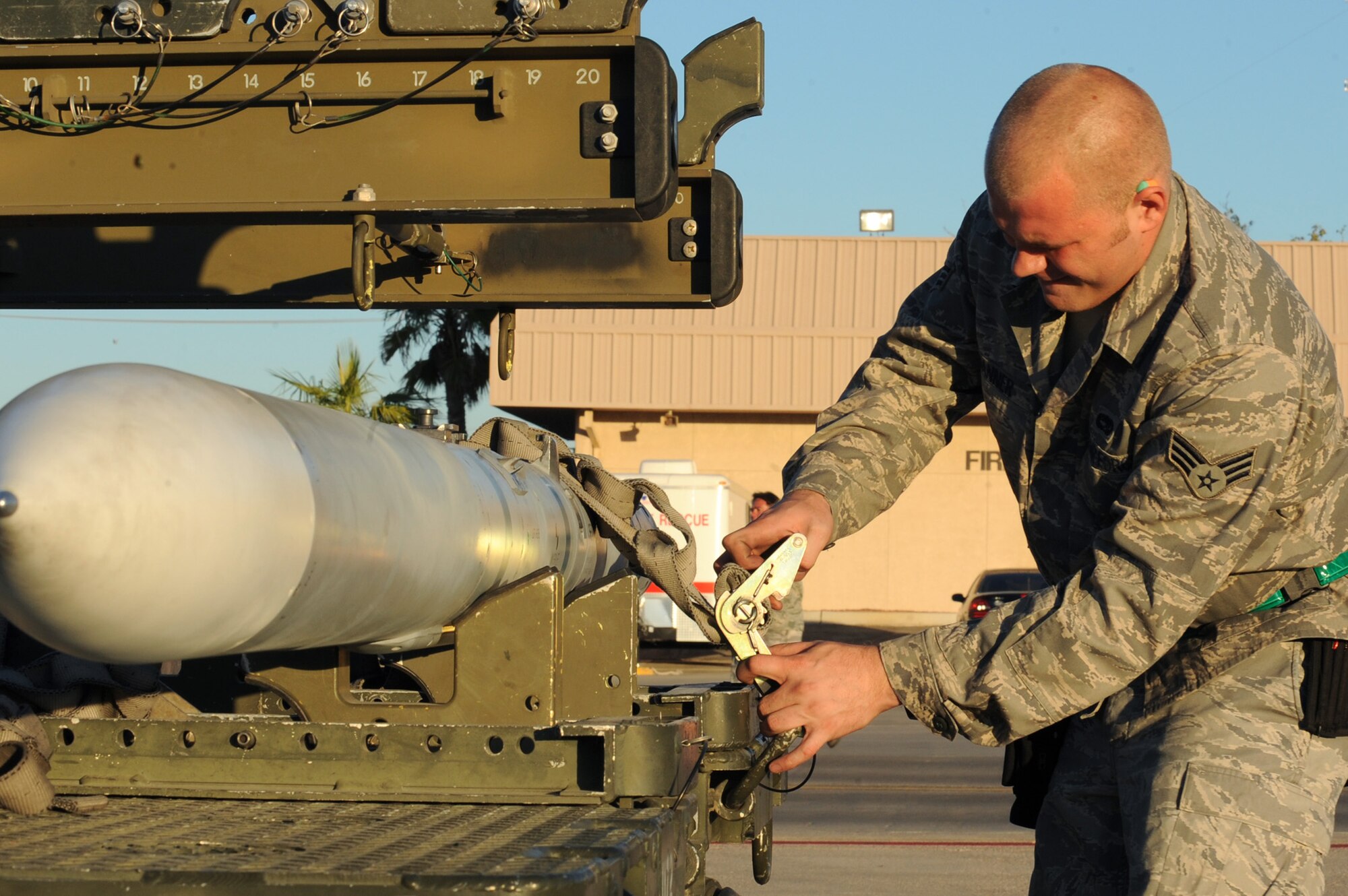 NELLIS AIR FORCE BASE, Nev.-- Senior Airman Dustin Danner, 57th Aircraft Maintenance Squadron works quickly to remove the cargo straps from an ordnance transporter during the Weapons Load Crew Competition on the Nellis flight line, Oct. 9, 2009. The bi-monthly weapons load crew competition tests the skills of Airmen on six different teams. The Airmen are judged on speed, accuracy and safety. 
(U.S. Air Force Photo / Airman 1st Class Jamie Nicley)

