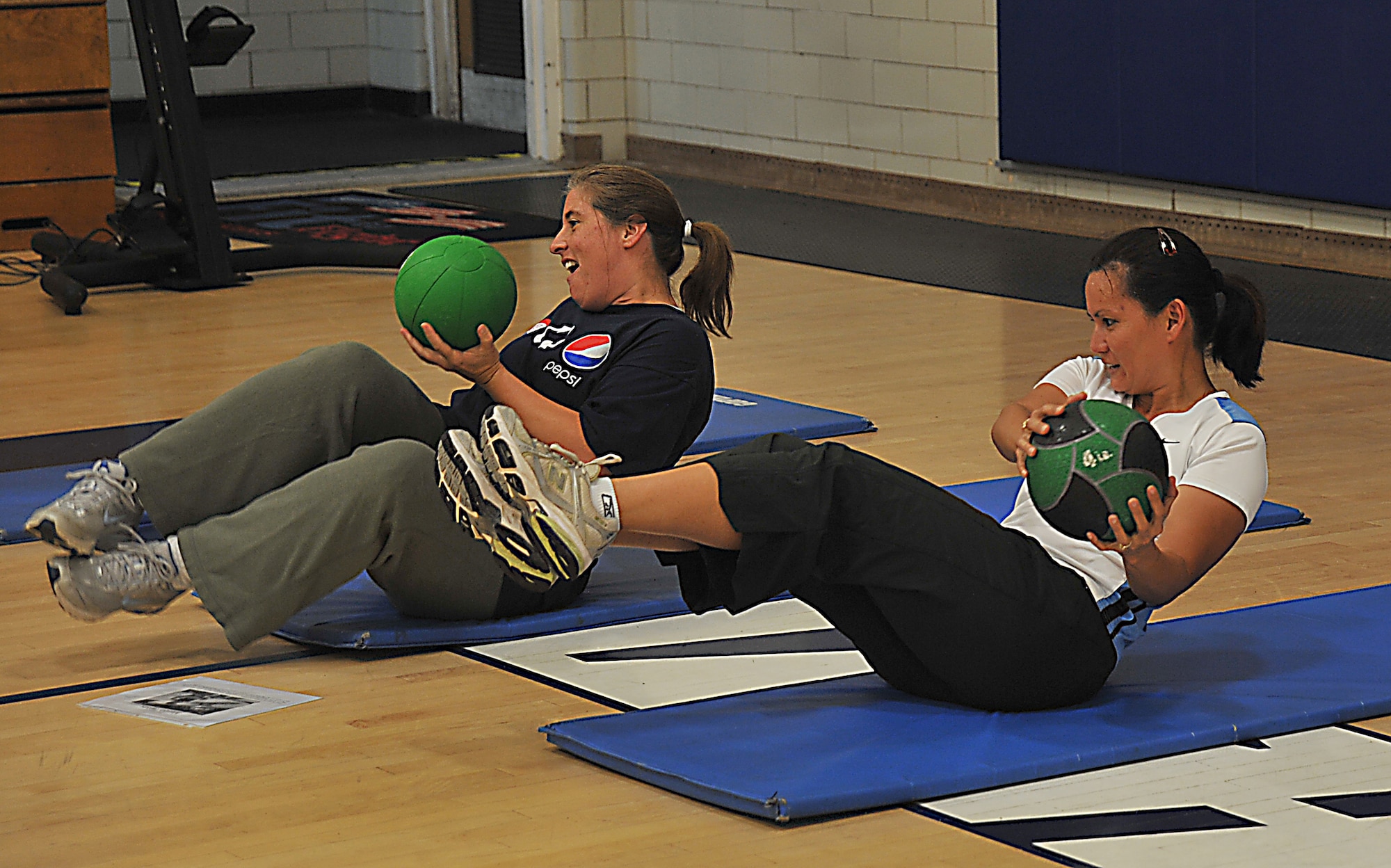VANDENBERG AIR FORCE BASE, Calif. -- Working their abdominal muscles with a weighted ball, Lynne Koertge (left) and Rose Leventis (right) get a quick workout during their lunch break at the Hard Core Fitness class at the base gym Wednesday, Oct. 14, 2009.  The class is a 30-minute, total body workout, which changes up with each instructor. (U.S. Air Force photo/Senior Airman Stephanie Longoria)