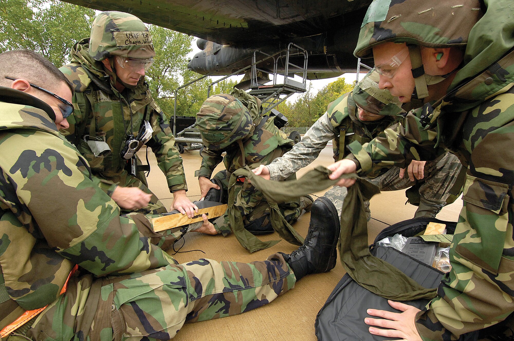 Practicing what they know during an exercise Oct. 8, members of the 76th Aircraft Maintenance Group’s aircraft battle damage repair team stop a B-52 emergency repair at a simulated deployed location and focus on a self-aid, buddy care scenario for an “injured” member of the group.  The team has a B-52 and a KC-135 at their training pad at Tinker that they can simulate battle damage and then learn how to perform repairs, keeping the Airmen ready for real-world calls from across the globe.  (Air Force photo by Margo Wright) 