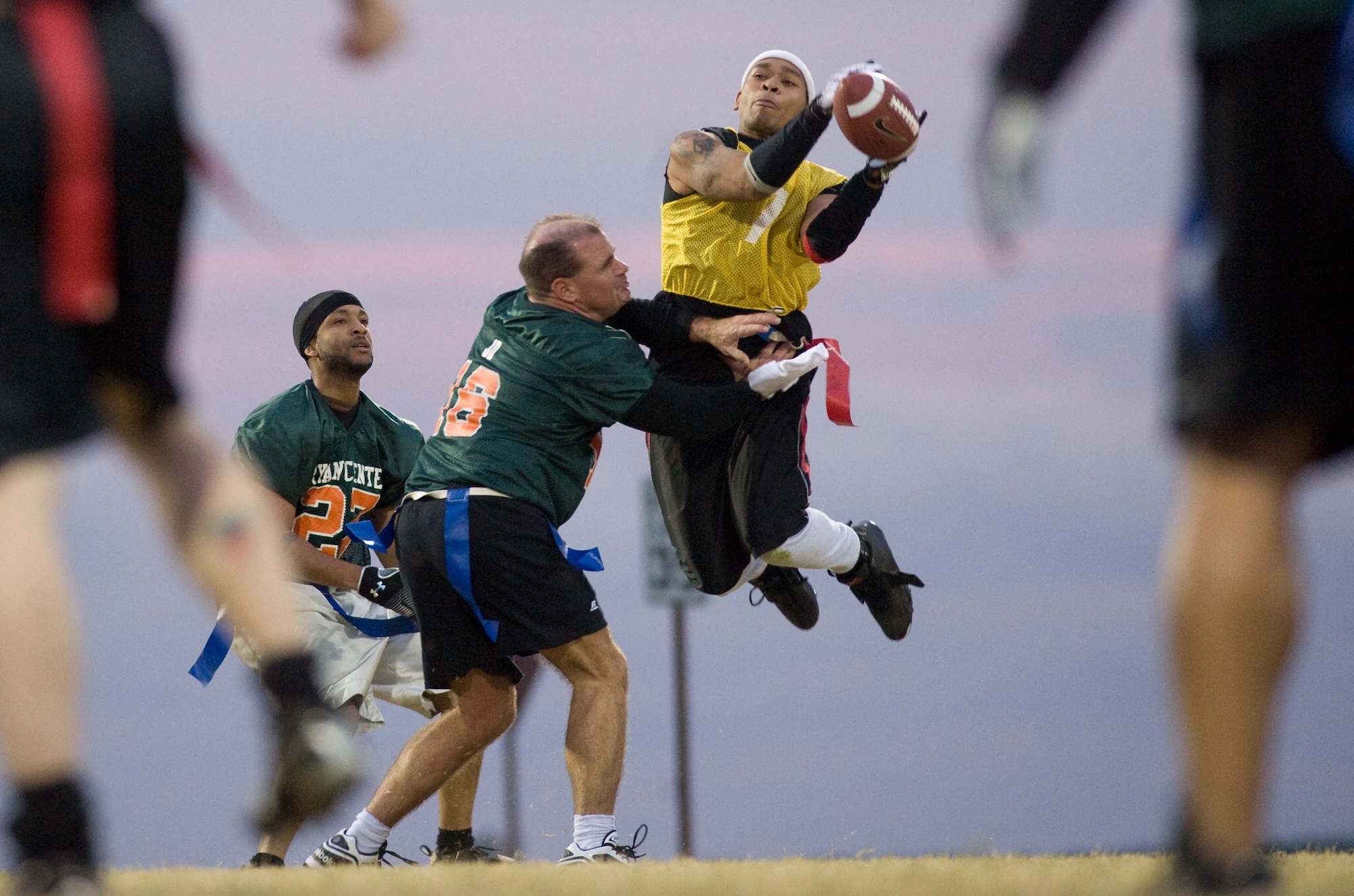 LANGLEY AIR FORCE BASE, Va. – Malchom Vines, 71st Aircraft Maintenance Unit, leaps past opponents Mike “Ziploc” Ray (left) and John “JD” Dever (center), ACC Operations Division, during a flag football game against the Ryan Center here Oct. 14. Ryan Center defeated 1st Aircraft Maintenance Squadron, 12-8. (U.S. Air Force photo/Staff Sgt. Barry Loo)