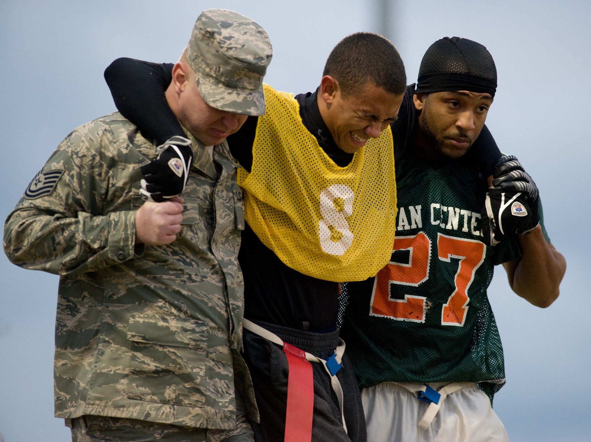 LANGLEY AIR FORCE BASE, Va. – David James (left), 71st Aircraft Maintenance Unit,  and Devon “Black Bambi” Reynolds (right), Ryan Center,  crutch Tory Stiggers (center), 27th Aircraft Maintenance Unit, after he injured his leg during a flag football game here Oct. 14. Ryan Center defeated 1st Aircraft Maintenance Squadron, 12-8. (U.S. Air Force photo/Staff Sgt. Barry Loo)
