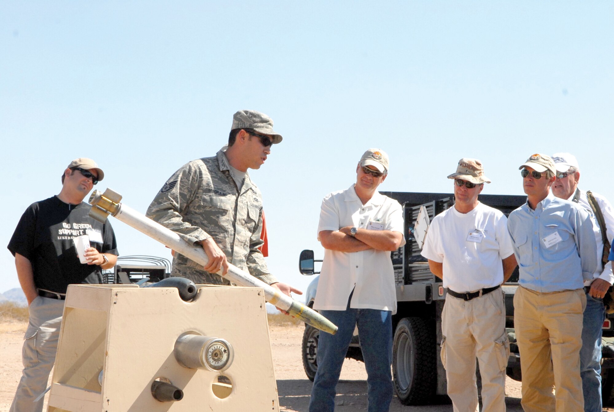 Staff Sgt. Benjamin McGraw, 56th Civil Engineer Squadron explosive ordnance disposal technician, holds a white phosphorus rocket while briefing civic leaders about the various ordnance.  Civic and business leaders from Luke Air Force Base, Davis-Monthan AFB and Fort Huachuca toured the Barry M. Goldwater Range Oct. 8 through 9 to get a better understanding of the range mission, capabilities and cultural assets. (U.S. Air Force courtesy photo)
