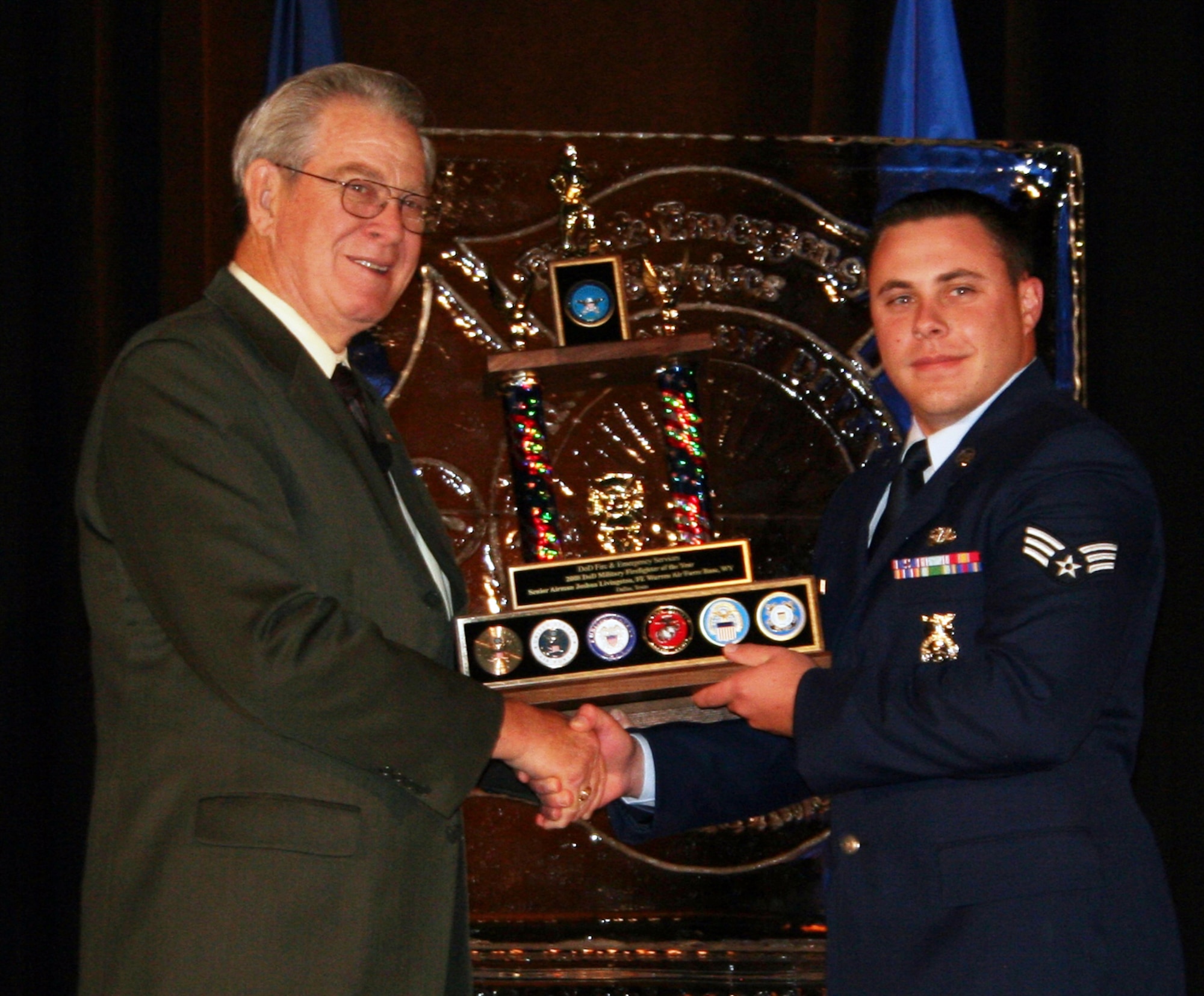 Senior Airman Joshua Livingston, 90th Civil Engineer Squadron, accepts his DoD Firefighter of the Year award from Bill Killen, former president of the International Assoiciation of Fire Chiefs, during as awards banquet Aug. 28 in Dallas. (Courtesy Photo)