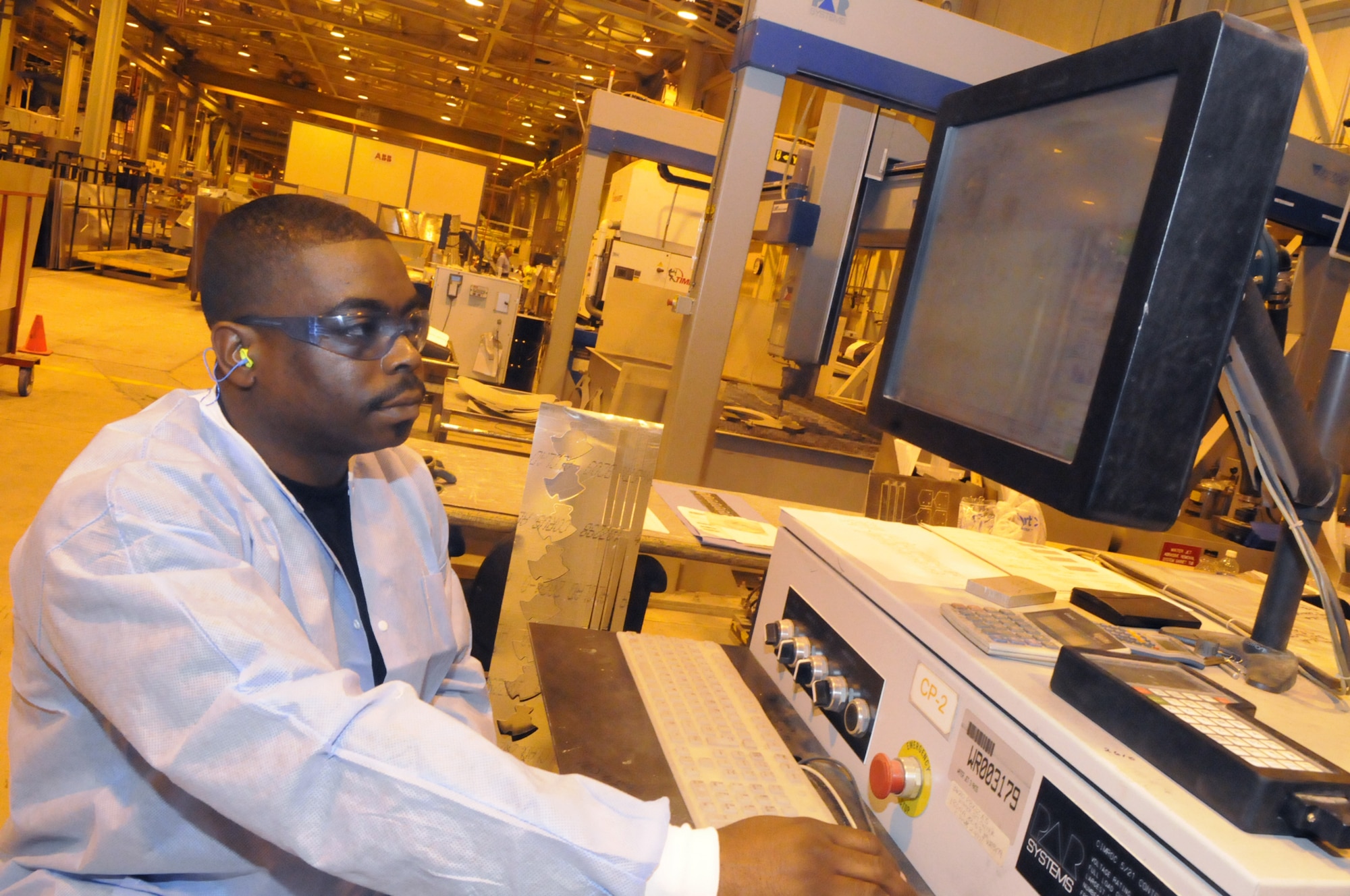 Jermaine Thomas runs the water jet computer program to cut  a rib for a C-130. U. S. Air Force photo by Sue Sapp