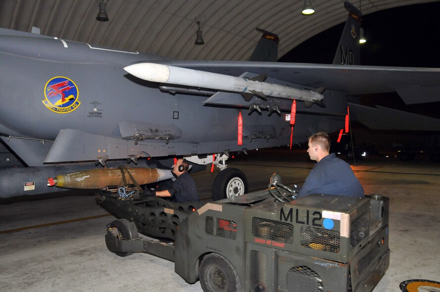 Staff Sgt. Matthew Modgling, weapons load team chief, steadies the loading of a  Mark 82 onto an F-15 as Senior Airman Nathan Harman, weapons load crew member, steers a "jammer" at Kunsan Air Base, Republic of Korea, Sept. 17. Sergeant Modgling and Airman Harman are assigned to the 389th Expeditionary Fighter Squadron, deployed from Mountain Home Air Force Base, Idaho. Throughout the week, 389th EFS weapons loaders, along with other Airmen and pilots, trained with live munitions. (U.S. Air Force photo/Capt. Shannon Collins) 