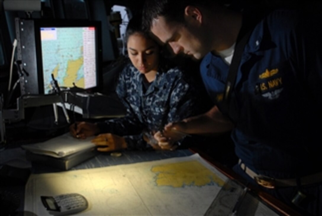 U.S. Navy Lt. j.g. Justin Short checks over navigational charts with Seaman Apprentice Stephane Razoarreola on the bridge of the guided-missile destroyer USS Cole (DDG 67) on Oct. 14, 2009.  The Cole is participating in Exercise Joint Warrior 09-2, a United Kingdom-led, multinational and multi-warfare exercise designed to improve interoperability between allied navies as well as to prepare for a role in combined operations during upcoming deployments.  
