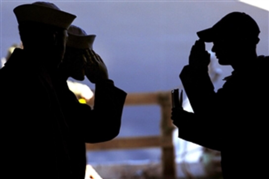 U.S. Navy  Seaman Anthony Gallo, an aviation ordnanceman, right, salutes and shows his identification card to Navy Petty Officer 2nd Class Abe Haw, the assistant junior officer of the deck, as he requests permission to come aboard the aircraft carrier USS John C. Stennis, which is docked in its home port at Bremerton, Wash., Oct. 8, 2009.