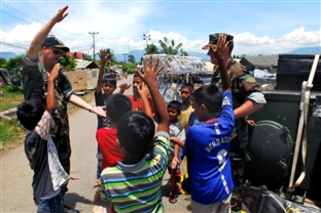 U.S. Navy Rear Adm. Richard Landolt, commander, Amphibious Force Seventh Fleet, teaches the “Gator Chomp” to Indonesian children outside the Humanitarian Assistance Rapid Response Team's medical tent in Padang, Indonesia, Oct. 10, 2009. Landolt visited the hospital, which is providing free medical treatment to Indonesian citizens of West Sumatra following two earthquakes. The "Gator Chomp" is a gesture made by fans of the University of Florida's sports teams.