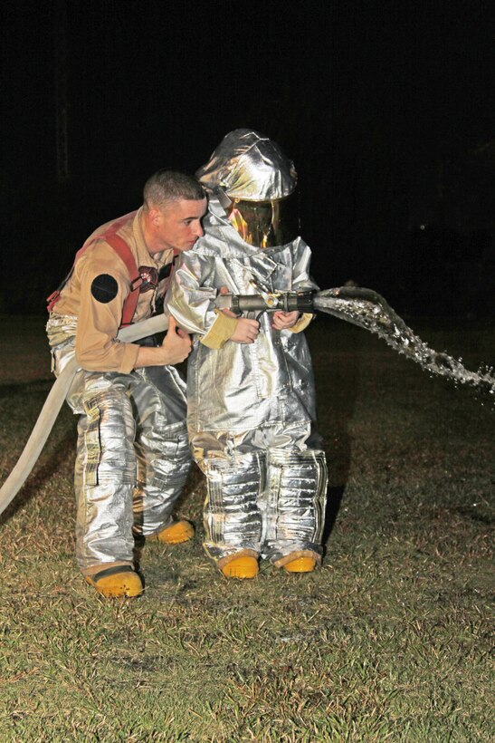 An aircraft rescue firefighter here helps a child operate a fire hose after dressing in proximity firefighting suits and running approximately five yards during a demonstration at the Matthew C. Perry Fall Festival at the M.C. Perry soccer fields here Oct. 16. The station fire department also provided a fire truck for the children to explore.