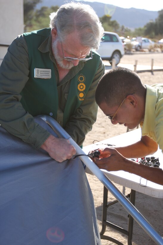 Lance Cpl. Gerardo Mangual, an ammunition technician with the Center Magazine Area, Company B, Headquarters Battalion, helps Les Snodgrass, a member of the board of directors for the Twentynine Palms Historical Society, take a tarp off a canopy after the Old Timers Reception at the Twentynine Palms Museum Oct. 15.  The Historical Society owns the museum and has been hosting the Old Timers Reception there since the first year it opened in 1995.