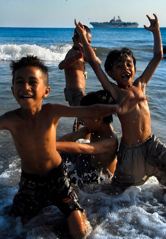 Local boys swim at the beach here Oct. 17 as the amphibious assault ship Bonhomme Richard sits anchored in the background. Aboard the ship are members of the 11th Marine Expeditionary Unit, in the country conducting jungle and urban training with other militaries and performing medical, dental, engineering, and community projects.
