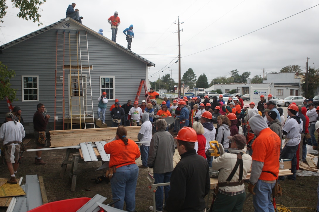 (NEW BERN, N.C.) One of the two houses built as part of Habitat for Humanities Blitz Build event stands with its exterior completed as some of the project’s volunteers, both military and civilian, gather around for the closing remarks. The builds’ goal is to ultimately supply new and furnished homes for the less fortunate families who struggle in today’s economic standard of living. (Marine Corps photo by Lance Cpl. Jonathan G. Wright)