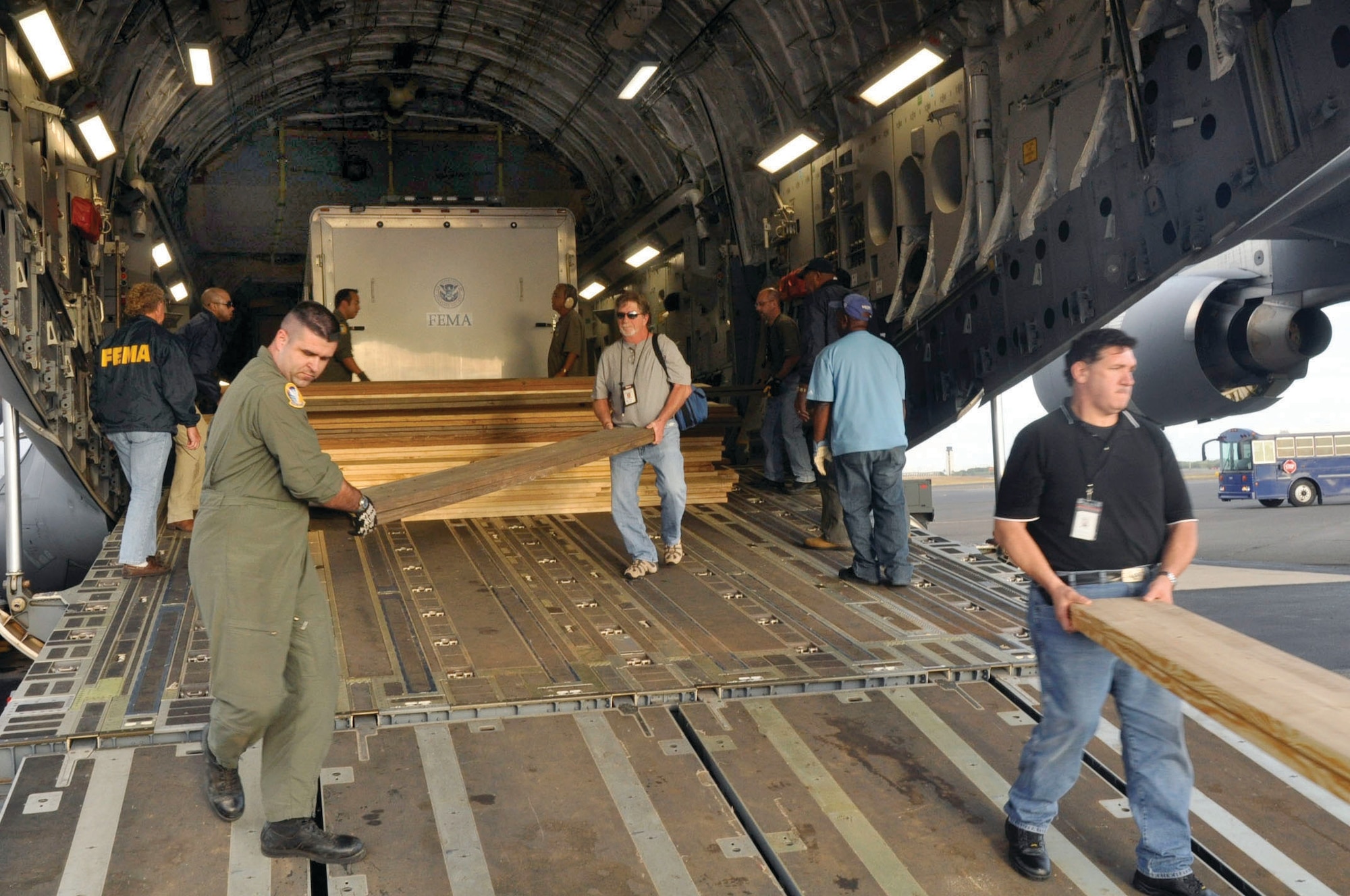 With the help of fellow aircrew and FEMA members, Tech. Sgt Mike Carrier (far left) off-loads wood planks from the back of a 729th Airlift Squadron C-17 at Hickam AFB in Hawaii. The C-17 flew from March ARB to Dobbins ARB, Ga., Oct. 2, where 16 members of FEMA and a FEMA truck and communications trailer were boarded and flown to Hickam AFB as part of the humanitarian support mission after an earthquake and tsunami devastated the region. After Hickam, the C-17 flew three FEMA passengers and five generators to Pago Pago. On the return flight, the March aircraft carried Army National Guard Soldiers, first responders and Anthony M. Babauta, U.S. Assistant Secretary of the Interior for Insular Areas. March remained on alert for further tsunami relief missions. (U.S. Air Force Photo/ Master Sgt. Daniel Nathaniel III)