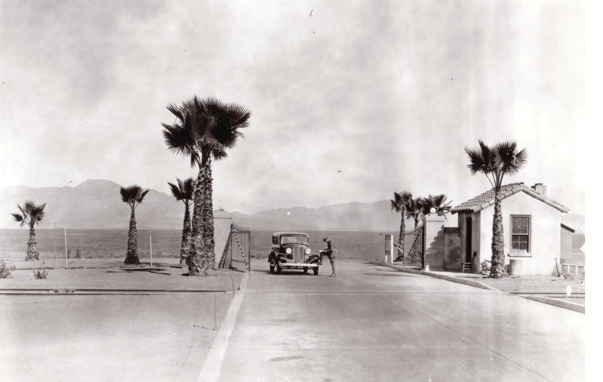 An Army Air Corps Military Policeman, the forerunner to our modern Security Forces, registers a vehicle at the new Main Gate at March Field, which still stands at the entrance to Green Acres where Meyer and Riverside Drives intersect. The Military Policeman is wearing his service dress uniform, which includes breeches and puttees. The Army Air Corps led the way in the change to straight trousers, which were universally adopted by the Army in 1937, with the exception of mounted troops. This photo was probably taken around 1934 or 1935, and features prominently the new palm trees planted around the base. Then Lieutenant Colonel Henry “Hap” Arnold, who assumed command of March Field in 1931, was not provided funding for landscaping for the new base, but was a master of public affairs. Colonel Arnold convinced a local farmer to donate trees, which he then placed at key points around the base. The palm trees that line Graeber Street in front of the Wing headquarters building date to the same period, and are now as tall as the flag pole that once dwarfed them. (Photo courtesy of March Field)