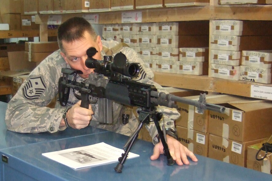 First Sgt. Troy Schrader looks down the scope of a weapon housed with the Small Arms Services and Support group, Baghdad, Iraq.  This is a group of civilian contractors that worked with the 193rd Special Operations Wing, Security Forces Squadron to repair any damaged equipment and issue any new equipment that needed distributing. 