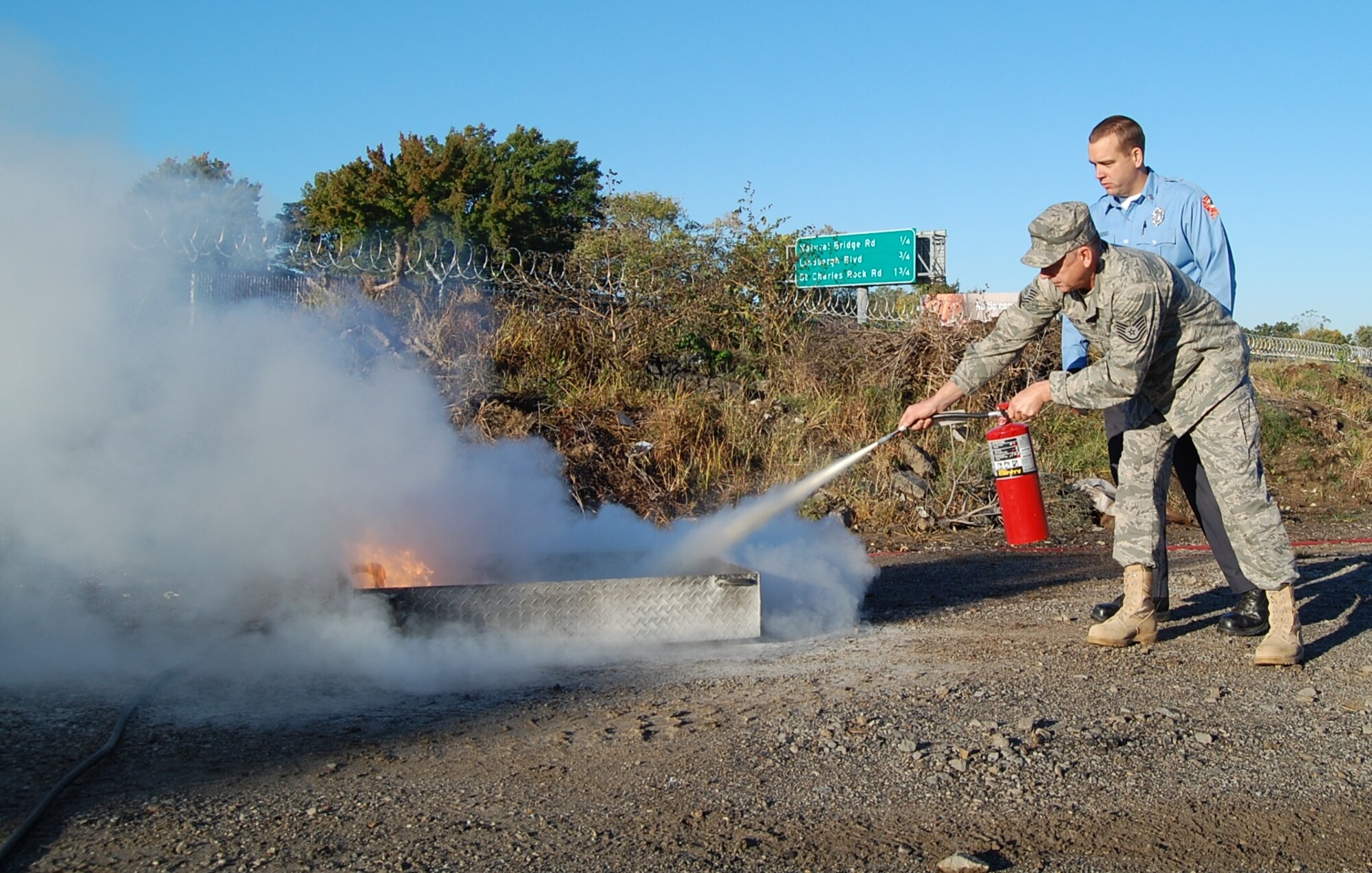 Master Sgt. Joshua Barnaby, 231st Civil Engineer Squadron firefighter, talks Tech. Sgt. Kenneth Kifer, 131st Logistics Readiness Squadron vehicle maintenance, through how to properly use a fire extinguisher to put out a fire Oct. 18. The 231st teamed up with a local fire department to help teach servicemembers fire safety in honor of Fire Safety Month. (Photo by Senior Airman Jessica Donnelly)