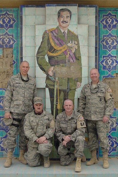 First Sgt. Troy Schrader, Master Sgt. Louis Lusk, Chief Master Sgt. Jerome Staquet, and Lt. Col. Kraig Artz stand with a tile portrait of Saddam Hussein in the courtyard within the Al Faw Palace Complex in Baghdad, Iraq.  The grounds of this palace complex are now a part of Camp Victory.                          