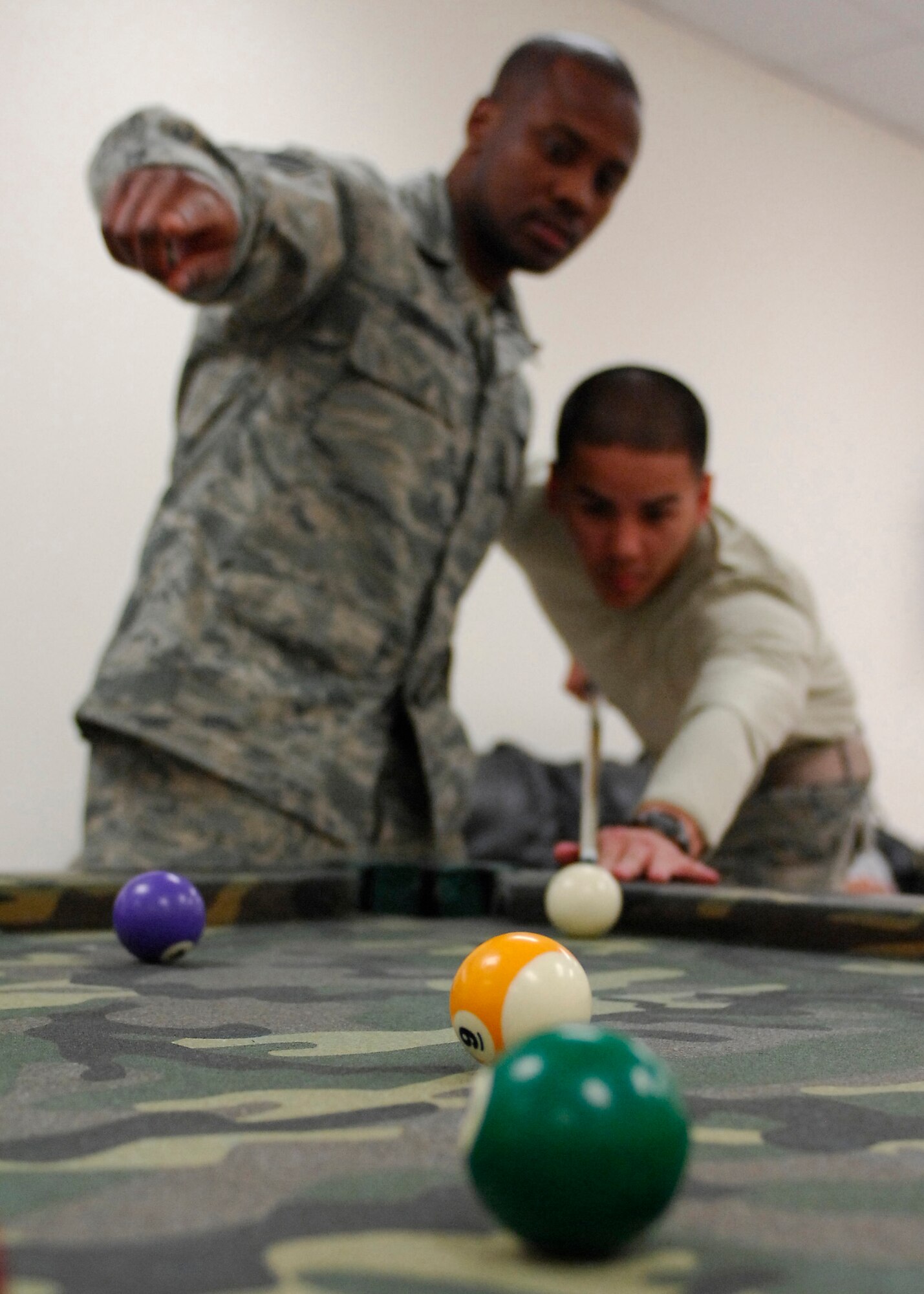 BAGRAM AIRFIELD, Afghanistan -- Staff Sergeant Torrance Townsend (left) gives Airman First Class John Anny (right) tips on how to get his striped nine ball to spin around the solid six. Segeant Townsend and Airman Anny are both supply troops with the 455th Expeditionary Logistics Readiness Squadron deployed from Langley Air Force Base, Va. Sergeant Townsend is from Hollandale, Miss., and Airman Anny is from Wahaiawa, Hawaii. (U.S. Air Force photo/Senior Airman Susan Tracy)