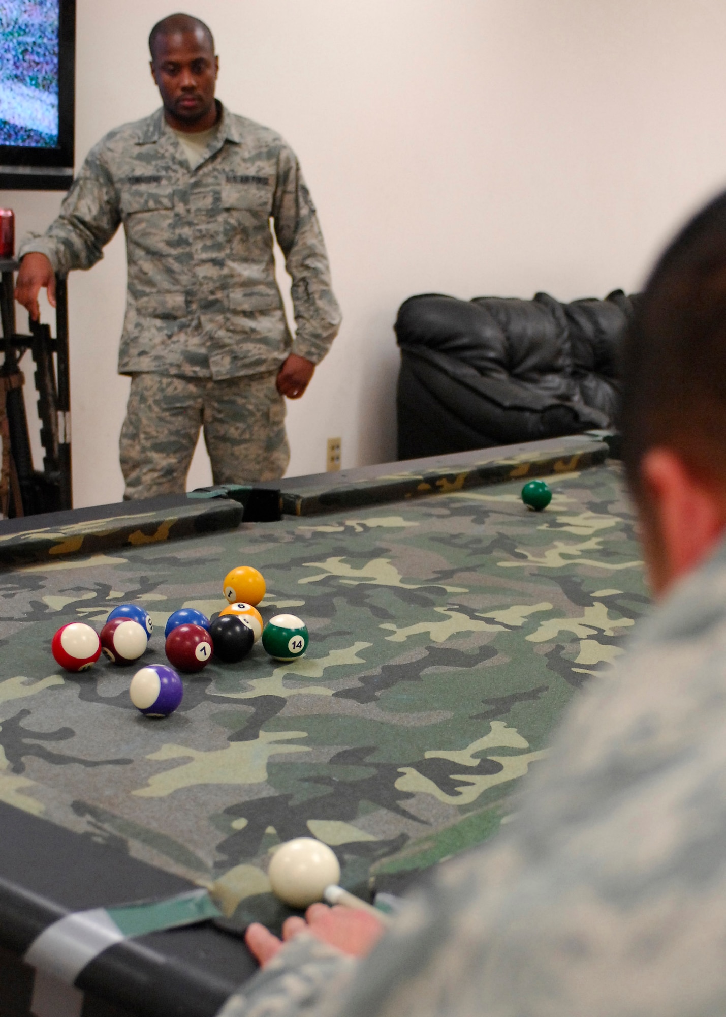 BAGRAM AIRFIELD, Afghanistan -- Staff Sergeant Torrance Townsend, a 455th Expeditionary Logistics Readiness Squadron supply troop deployed from Langley Air Force Base, Va., watches as Airman First Class John Anny concentrates on lining his next shot up perfectly in their game of pool. Airman Anny, a Wahaiawa, Hawaii native also works in supply and is deployed from Langley AFB. Sergeant Townsend is originally from Hollandale, Miss. (U.S. Air Force photo / Senior Airman Susan Tracy)
