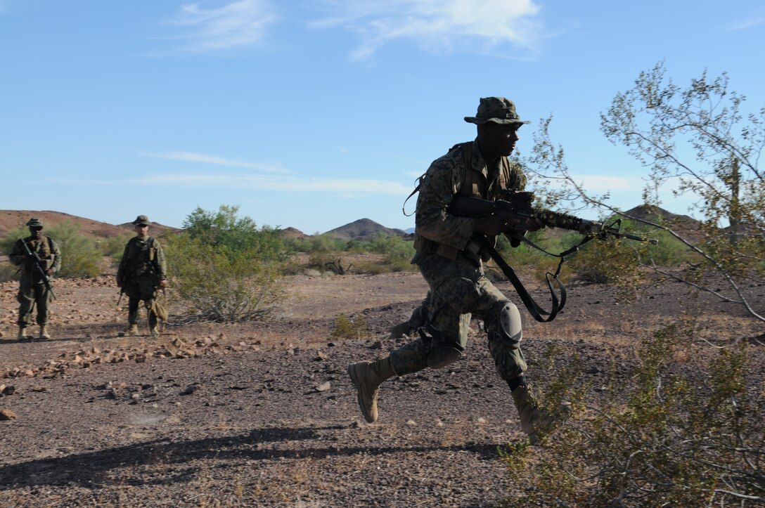 A Marine from Headquarters and Service Company, 1st Battalion, 2nd Marine Regiment, rushes forward as his fellow Marines look on during infantry tactics training at Graze Range at the U.S. Army Yuma Proving Ground in Arizona, Oct. 18, 2009. Comprised of Marines with noninfantry specialties, the Camp Lejeune, N.C.-based company is preparing to operate as an infantry company during their upcoming deployment to Afghanistan in the spring of 2010.