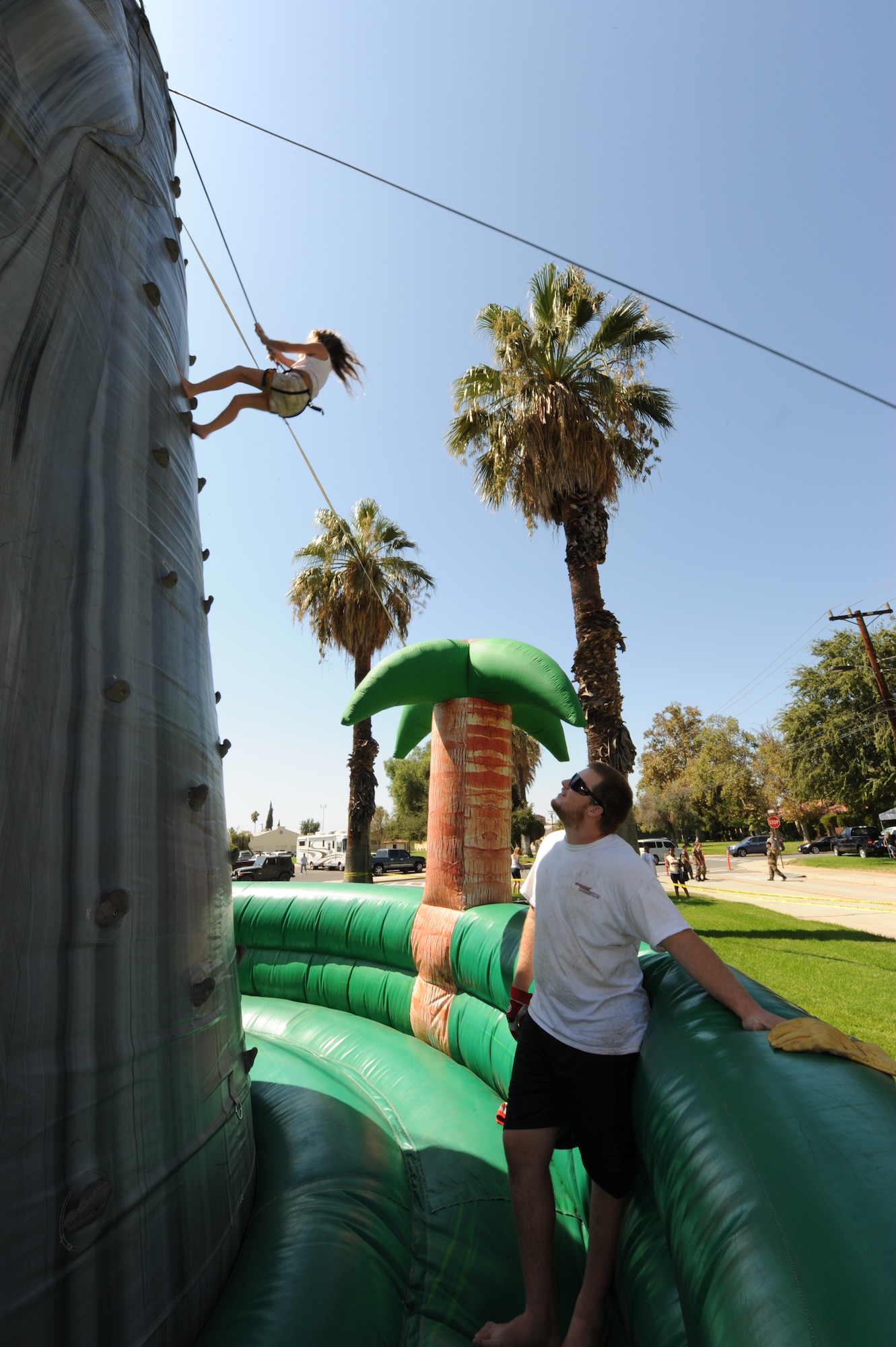 Nick Polk, from a local jumpers company, observes 8 year-old Rachel as she climbs to the top of an inflatable wall during the March ARB, Calif., annual picnic. (U.S. Air Force photo taken by Staff Sgt. Erica J. Knight) 