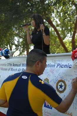 Staff Sgt. Angel Gallardo, a photographer with 4th Combat Camera Squadron, signs a banner during the annual picnic.  The banner will be displayed at the base passenger terminal for deploying and returning troops to see.  (U.S. Air Force photo by Technical Sgt. Joe Zuccaro) 