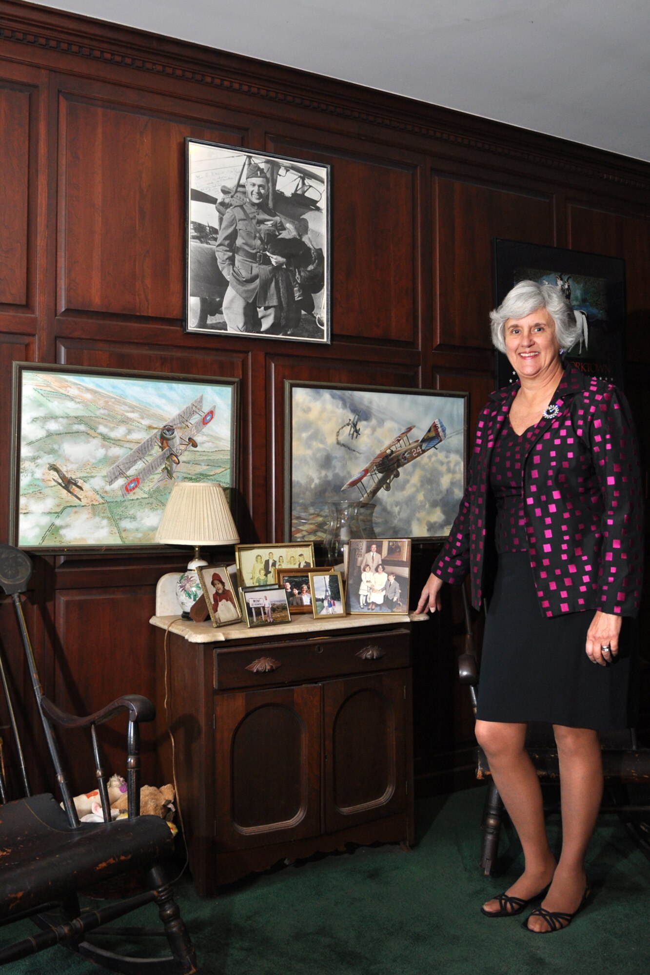 Susan d’Olive Mozena, Daughter of 1st Lt. Charles R. D’Olive, a WWI Ace with the 93rd Pursuit Squadron in France in 1918, poses in front of two paintings commissioned to recreated her father’s triumphs in WWI and a photograph of the man himself.   Master Sgt. Greg Steele, 47th Fighter Squadron, visual information specialist, traveled to Detroit, Mich., to gather photos and documents from Mrs. d’Olive Mozena concerning her father’s role in the history of the 93rd BS, which is part of the 917th Wing at Barksdale Air Force Base, La. The items will be used in historic displays at the 917th Wing headquarters building in the future. The most famous painting (on the right) was of Lieutenant D’Olive’s 5th kill (Oct 18, 1918). The artwork is a 24x36 water color painting by Douglas Carrick from Prestwyck, Scottland in 1960. (U.S. Air Force photo/Tech. Sgt. Jeff Walston)